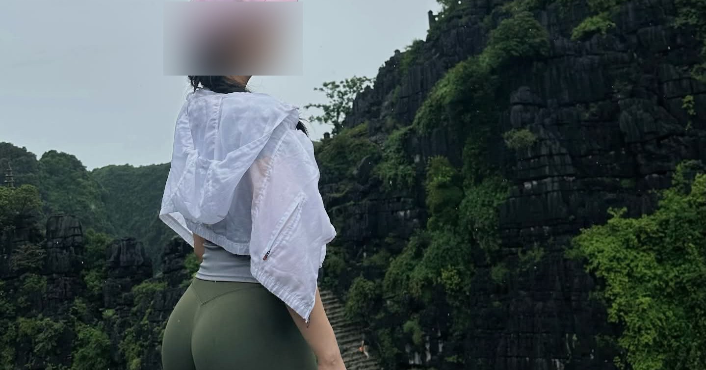 Cô gái mặc trang phục thể thao đứng giữa khung cảnh núi đá