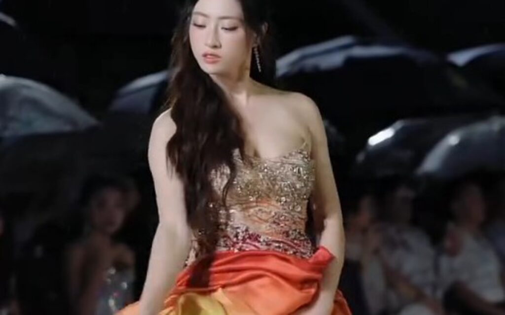 Lương Thùy Linh trình diễn trên sân khấu ngoài trời trong bộ váy màu cam đỏ