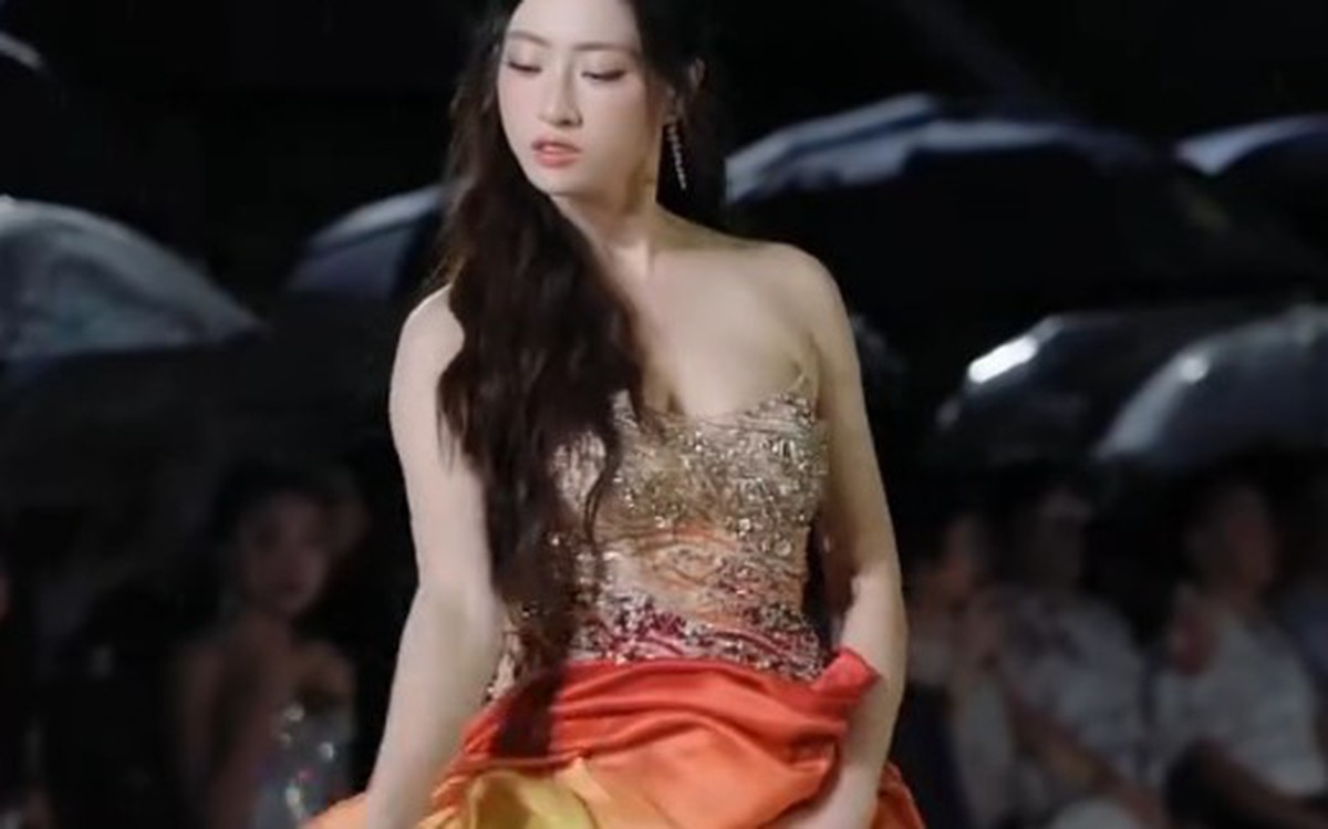 Lương Thùy Linh trình diễn trên sân khấu ngoài trời trong bộ váy màu cam đỏ