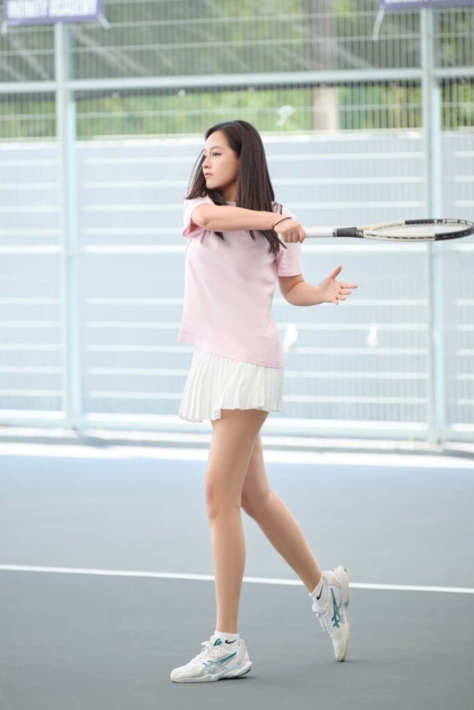 Chanh Coco trên sân tennis với trang phục thể thao và cây vợt
