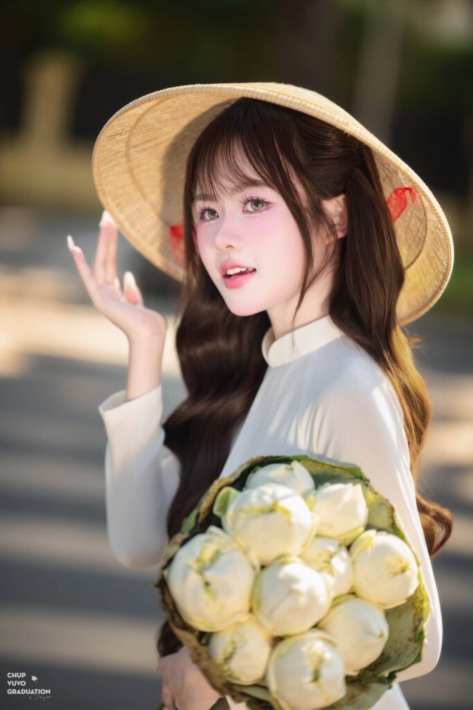 Quỳnh Hoa chạm tay vào vành nón lá khi chụp ảnh