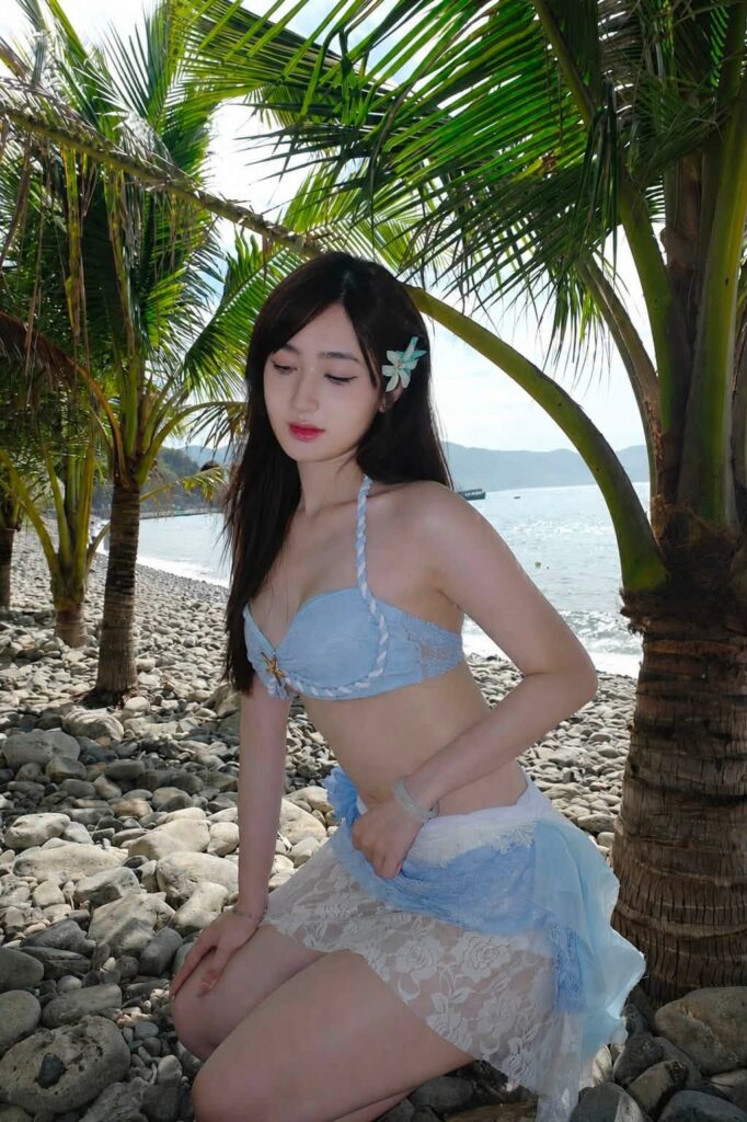 Ngọc Thủy đứng dưới tán dừa trong bộ trang phục đi biển