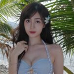 Ngọc Thủy diện bikini xanh pastel giữa khung cảnh biển và hàng dừa