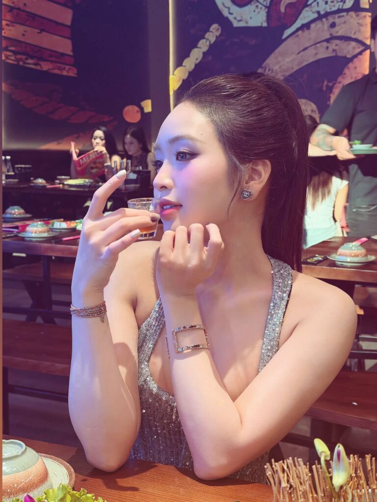 Lê Phương Anh nghiêng người bên bàn ăn trong bộ váy hai dây