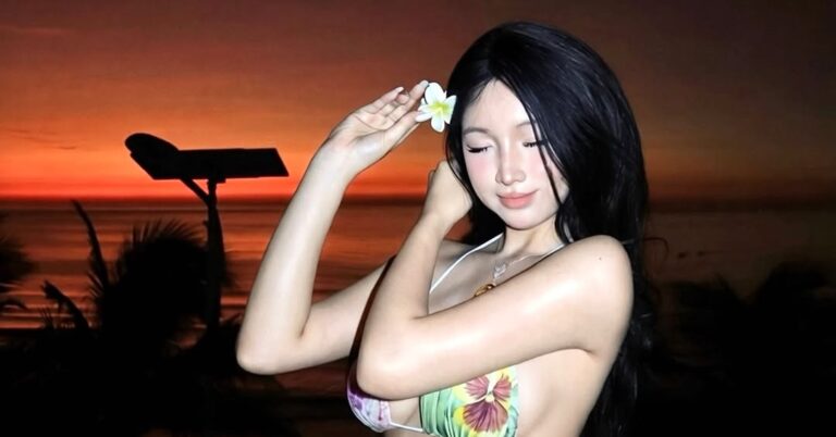 Nhi Thỏ đứng bên lan can hướng ra biển trong ánh bình minh