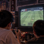 Hai tay cầm đặt trước màn hình trong một buổi chơi game bóng đá