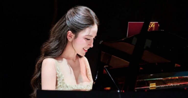 Vivi Pham diện đầm dạ hội màu kem ngồi bên cây đàn piano