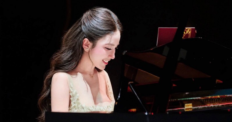 Vivi Pham diện đầm dạ hội màu kem ngồi bên cây đàn piano